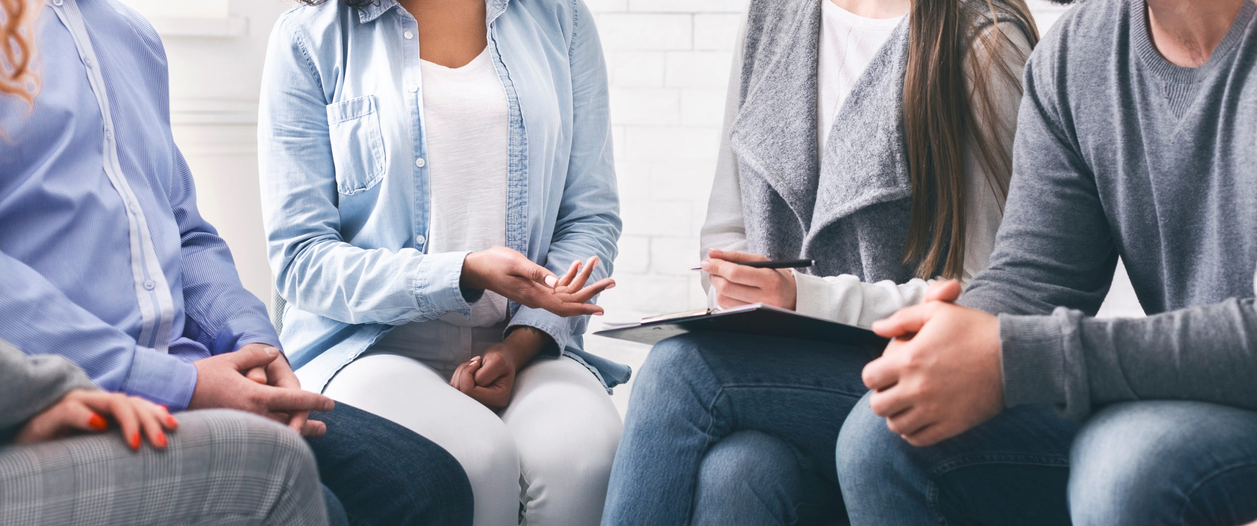 Counselor with clipboard talking to patients at office photo of a women giving a hug to another person